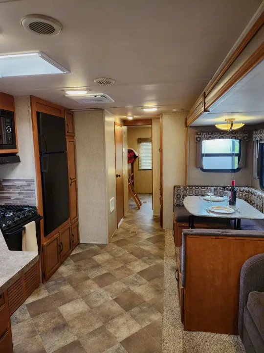 Cozy RV rental interior showing a dining area set for two, kitchen with appliances, and a hallway. Perfect for travel.. Palomino Puma 2016