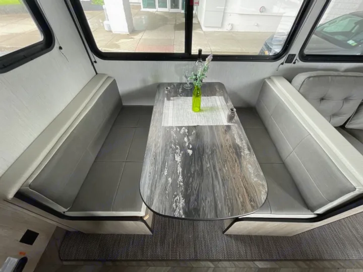 Explore this cozy RV rental interior featuring a stylish dinette with bench seating and a wood-look table, perfect for meals on the go.. Heartland RVs Prowler 2022