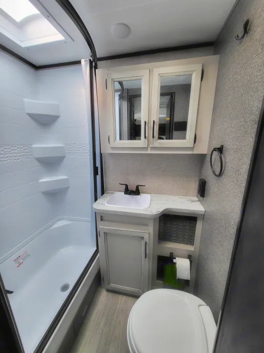 Step inside this RV rental bathroom featuring a bright shower, modern vanity with sink, and toilet. Ready for your adventure!. Jayco Jay Feather Micro 2022