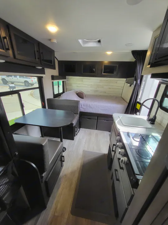 RV rental interior featuring a kitchen with stove, bed, dining booth, and storage, ideal for compact travel living.. Jayco Jay Feather Micro 2022