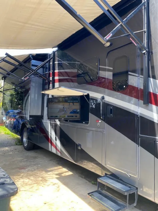 Enjoy outdoor entertainment with this spacious RV rental, featuring a TV and extended awnings for shade.. Thor Challenger 2019