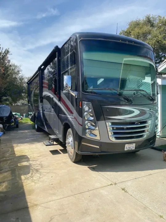 Sleek black rv rental motorhome with steps extended, parked on a bright driveway.. Thor Challenger 2019