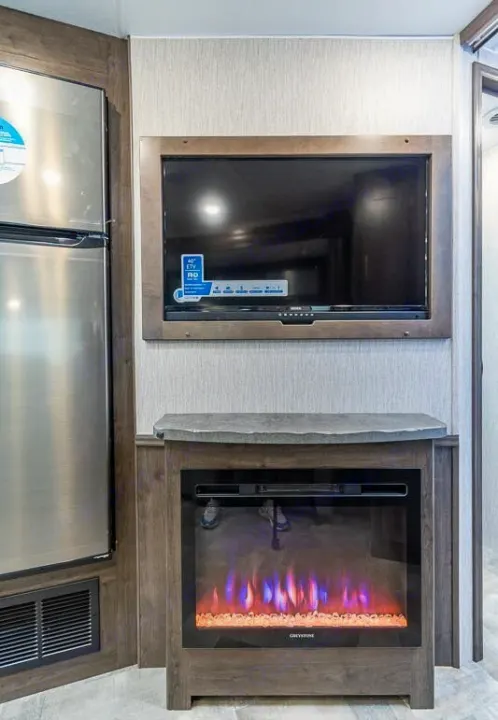 RV rental interior features: a modern TV, electric fireplace, and stainless steel refrigerator.. Coachmen Pursuit 2022