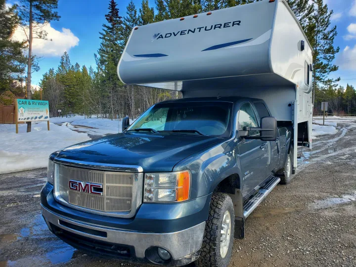 GMC truck with Adventurer RV for rv rental, parked on snowy, muddy ground near a Car & RV Wash sign.. Adventurer Adventurer 2020