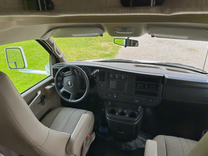Experience the journey! Inside an RV rental, showing the driver's cabin with dashboard, steering wheel, and road ahead.. Thor Coleman 2023