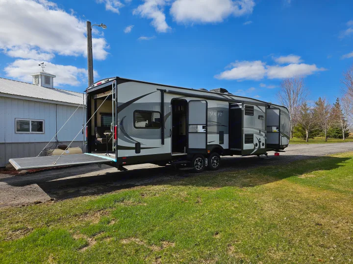 Spacious RV rental, a grey travel trailer with open doors and a rear ramp patio, parked outdoors.. Forest River XLR Hyperlite 30HDS 2017