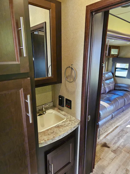 Modern RV rental: bathroom vanity with sink, reflecting a spacious living area with comfy leather seating.. Forest River XLR Hyperlite 30HDS 2017