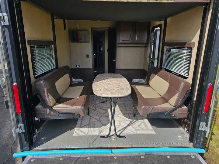 Toy hauler RV rental interior: versatile living space with two upholstered benches, a table, window blinds, and durable floor.. Forest River XLR Hyperlite 30HDS 2017