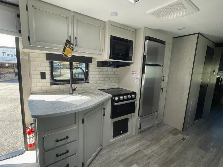 Explore this modern RV rental kitchen: light gray cabinets, white marble-look counter, subway tile, and full appliances.. Jayco Jay Flight 2022