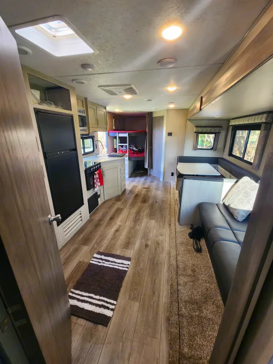 Modern RV rental interior with kitchen, dinette, and bunk beds visible. Hardwood floors and soft carpet blend for comfort.. Coachmen Catalina 263 bunk 2022
