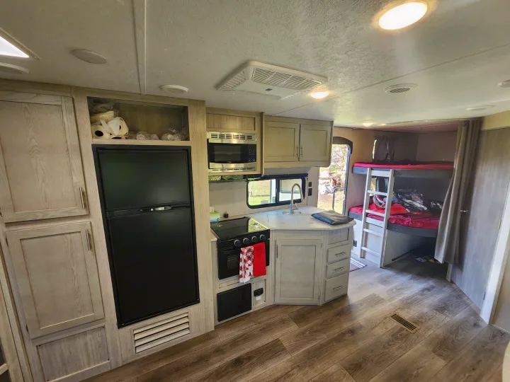 Well-appointed RV rental interior: kitchen with fridge, microwave, stove, sink, plus visible bunk beds.. Coachmen Catalina 263 bunk 2022