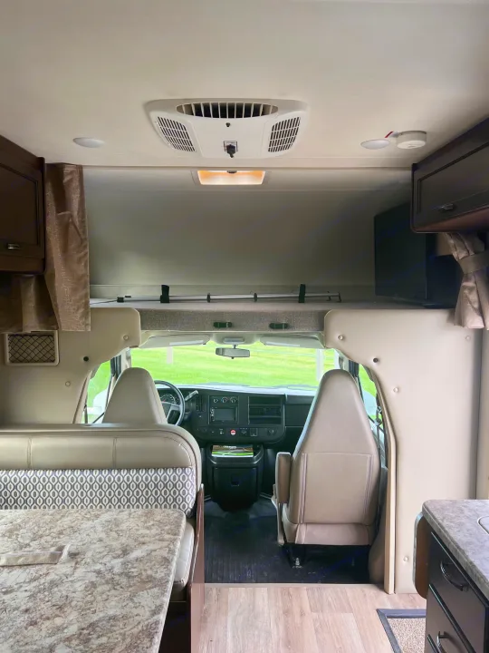 Spacious RV rental interior. View of the motorhome's cockpit, swivel seats, and a dining/living area with granite-look counters.. Thor Freedom Elite 2020