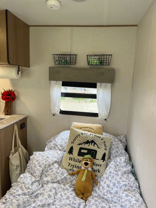 Cozy RV rental interior: Floral bedding, "Sorry for what I said..." pillow, Yogi Bear, window, and wall storage.. Forest River Other 2022