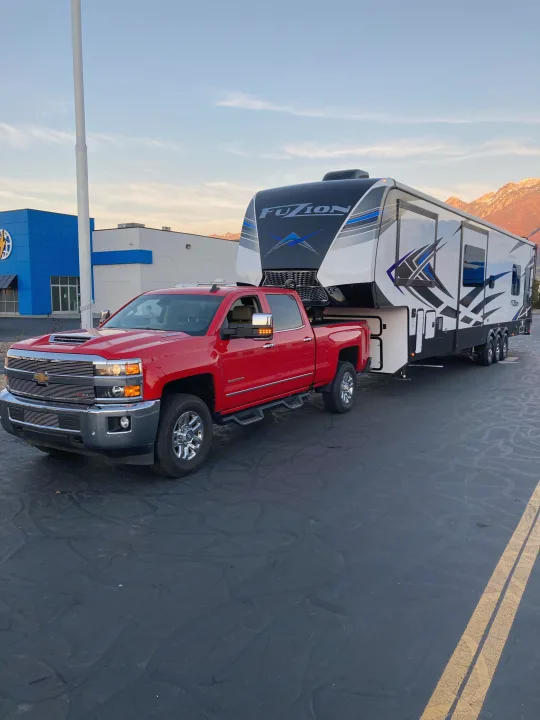 Red Chevy truck and large Fuzion fifth-wheel RV parked, ideal for your next rv rental adventure.. Keystone Fuzion 2021