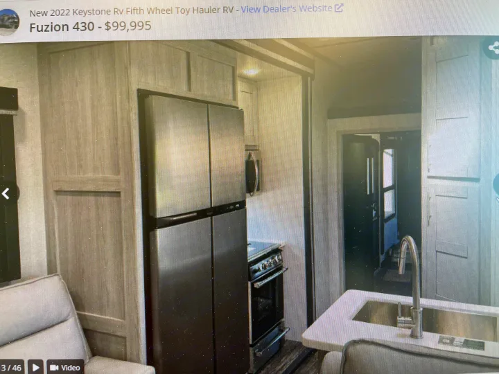 Spacious Keystone Fuzion toy hauler RV interior featuring a modern kitchen, large fridge, and hallway access. Perfect for RV rental.. Keystone Fuzion 2021