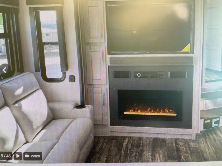 Cozy RV rental living space featuring a comfortable sofa, wall-mounted TV, and electric fireplace for a relaxing journey.. Keystone Fuzion 2021