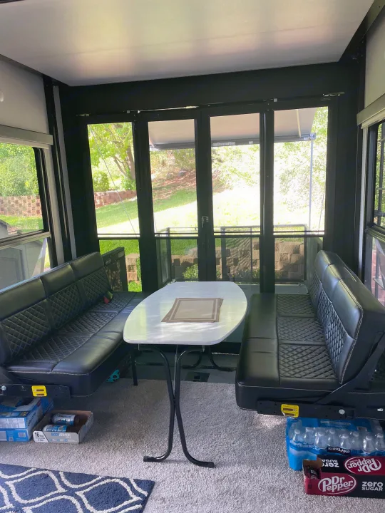 RV rental interior: cozy dinette with black quilted benches, white table, and outdoor views for comfortable travel.. Keystone Fuzion 2021