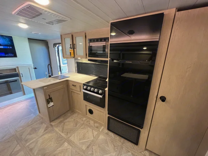 Modern RV rental interior featuring a bright kitchen with light wood cabinets, sleek black appliances, and a spacious feel.. Forest River Salem cruise lite 2023