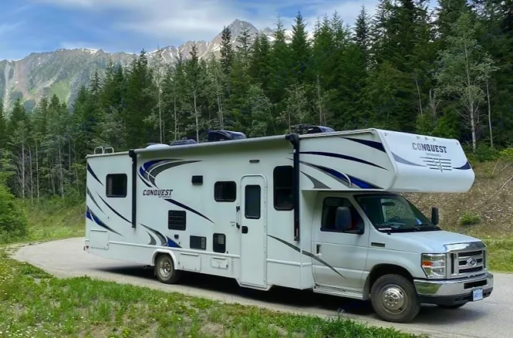 Explore nature in this Conquest rv rental, parked on a scenic mountain road surrounded by tall trees.. Gulf Stream Conquest 2017