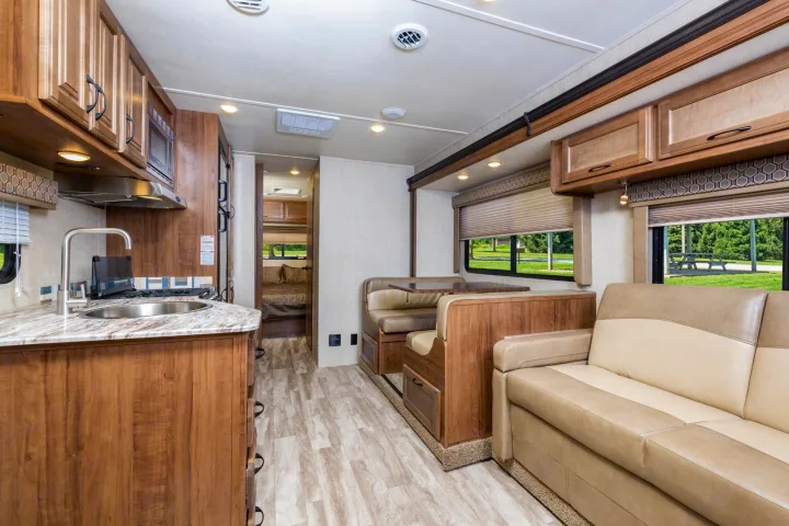 Spacious RV rental interior: well-appointed kitchen, dining booth, and sofa. Ready for comfortable travel.. Gulf Stream Conquest 2017