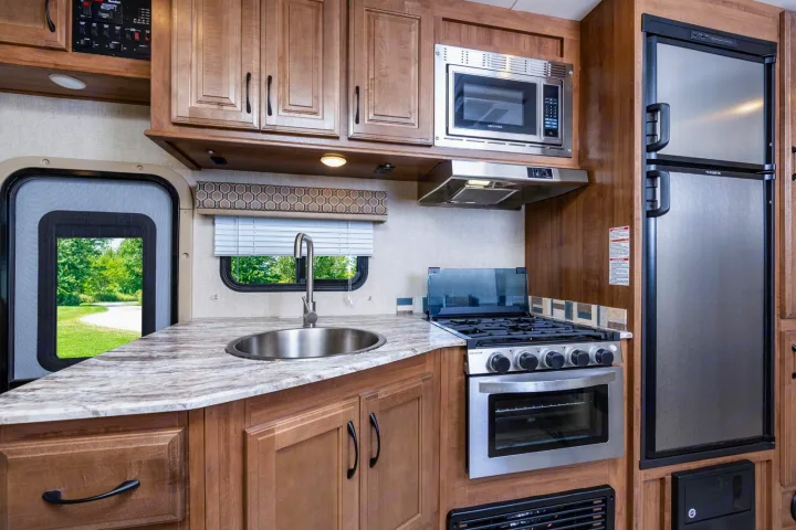 This RV rental's kitchen features a sink, oven, microwave, and refrigerator, all within a compact, functional space.. Gulf Stream Conquest 2017