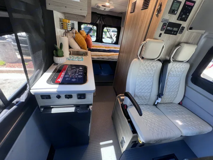 Inside an RV rental camper van: compact kitchen, cozy bed, and swiveling seats for a comfortable travel experience.. Winnebago SOLIS 59 PX 2023
