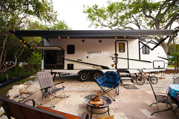 RV rental campsite showing an extended awning, outdoor kitchen, patio with fire pit & chairs. Perfect for camping.. Crossroads RV Sunset Trail Super Lite 2022