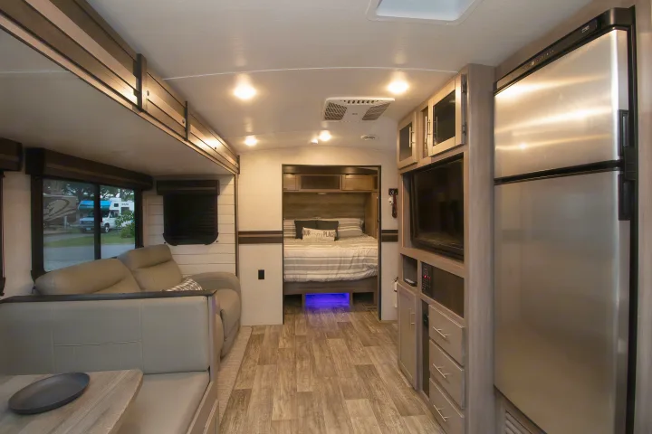 Spacious RV rental interior featuring a bright living area, cozy bedroom with blue lights, and full kitchen. Ideal for travel.. Crossroads RV Sunset Trail Super Lite 2022