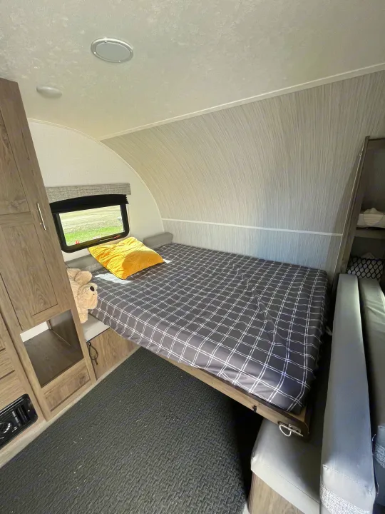 Travel trailer rv rental: a cozy bedroom with plaid bed, yellow pillow, and storage.. Forest River Coachman Clipper 2022