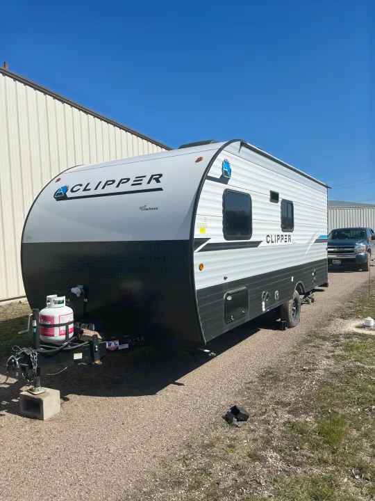 RV rental: A white and black "Clipper" travel trailer is parked on gravel next to a metal building.. Forest River Coachman Clipper 2022