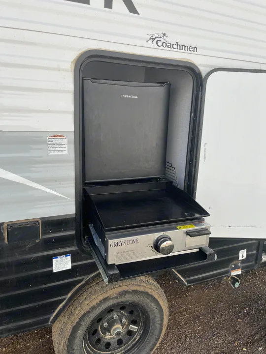 An RV rental's outdoor kitchen, showing a Greystone griddle, an Ever Chill mini-fridge, and LP quick connect. Perfect for camping.. Forest River Coachman Clipper 2022