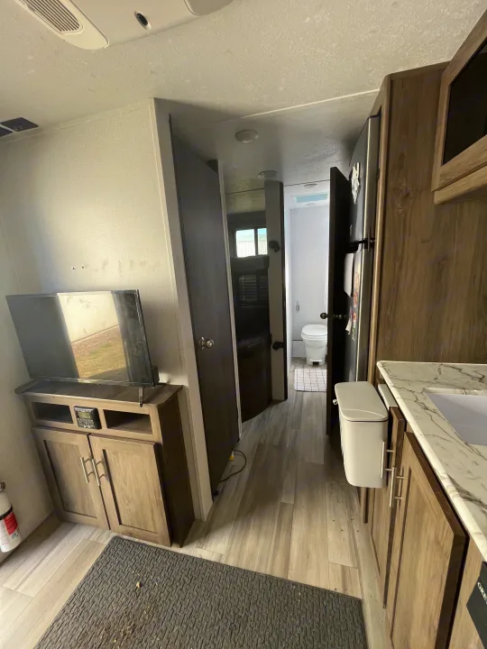 RV rental interior: TV/living area, compact kitchenette, and hallway leading to a bathroom. Functional camper living space.. Forest River Coachman Clipper 2022
