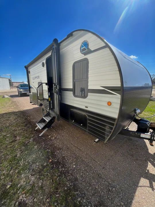 A light-colored Clipper travel trailer, perfect for RV rental, with its entry steps lowered on a sunny day.. Forest River Coachman Clipper 2022