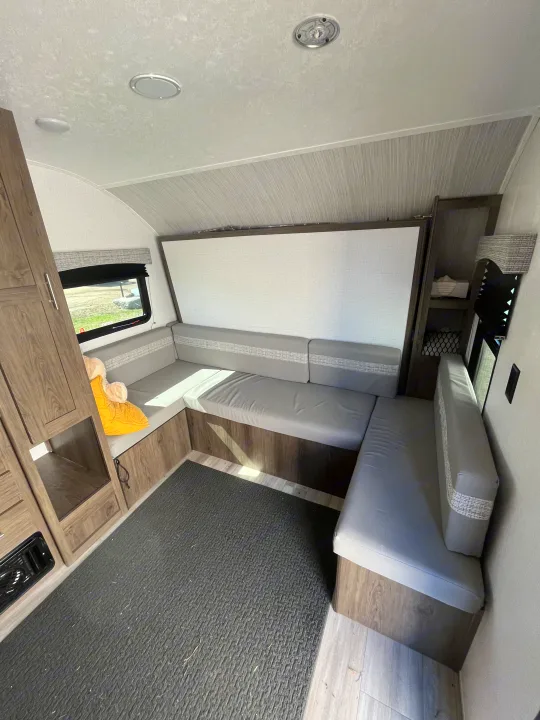 RV rental interior featuring a U-shaped dinette with gray cushions, wood cabinetry, and bright lighting.. Forest River Coachman Clipper 2022
