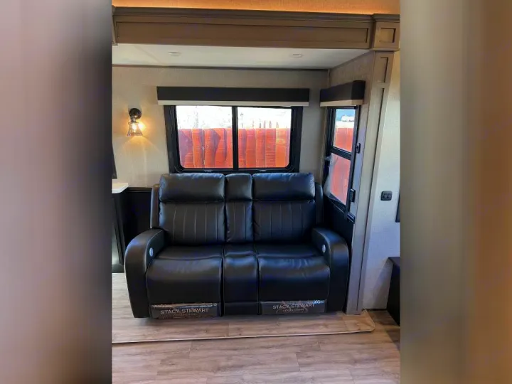 Inside an RV rental: a plush black leather reclining sofa and bright windows offer a cozy, modern living space.. Jayco Pinnacle 2022
