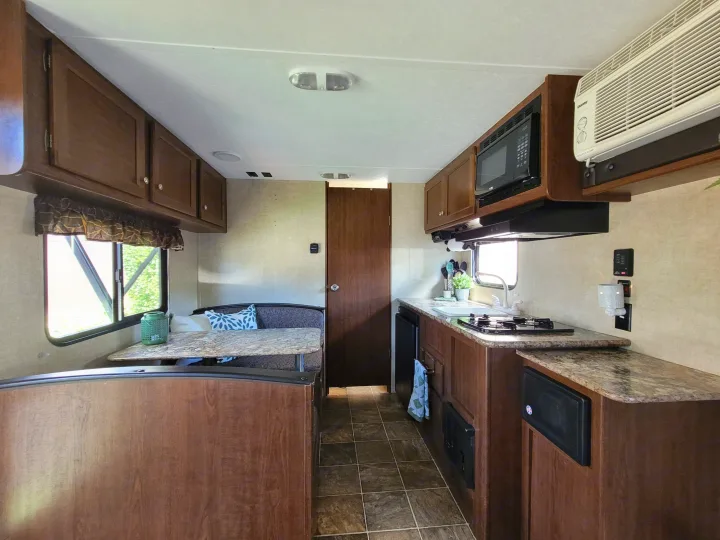 Comfortable RV rental interior showcasing a well-equipped kitchen with stovetop, microwave, and a cozy dinette.. Keystone RV Hideout LHS 2016