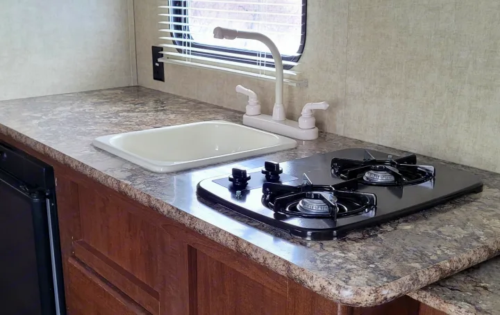 Compact RV rental kitchen: functional space with sink, two-burner cooktop & durable counter.. Keystone RV Hideout LHS 2016