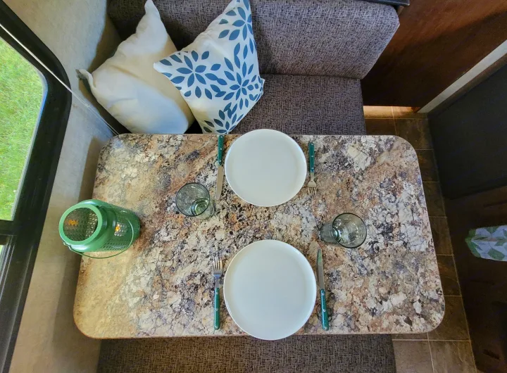 RV rental dining area with granite-like table, two place settings, and window view. Cozy travel space.. Keystone RV Hideout LHS 2016