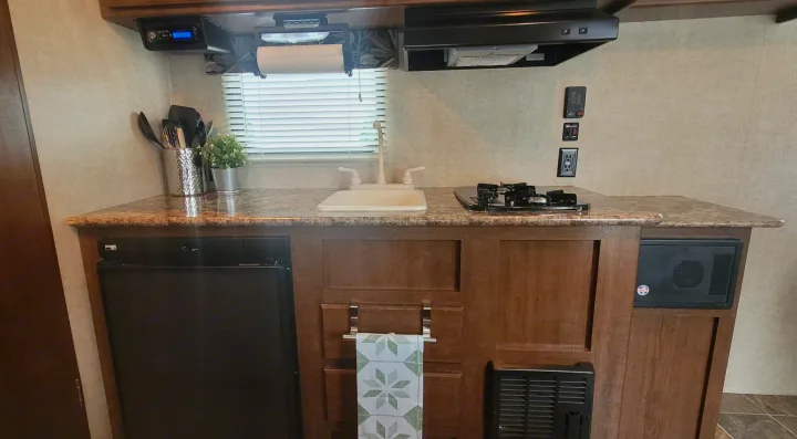 This RV rental kitchen offers a practical setup with a stove, sink, small fridge, and built-in amenities.. Keystone RV Hideout LHS 2016