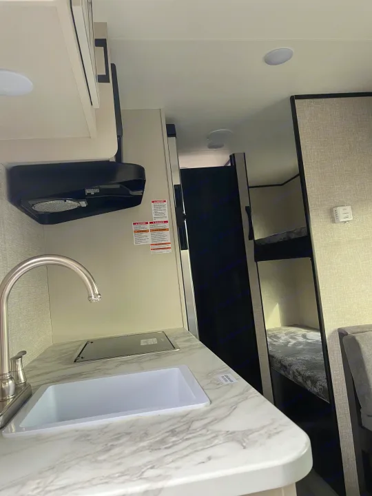 Compact RV rental interior featuring a kitchenette with sink, faucet, and portable cooktop.. Jayco Jay Flight SLX STX Edition 2022