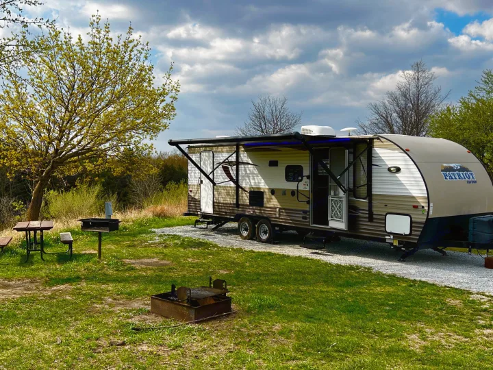 This RV rental is perfectly set up at a spacious campsite, featuring a picnic table, grill, and fire pit for camping fun.. Forest River Forrest River Cherokee Patriot Edition 26DBH 2015