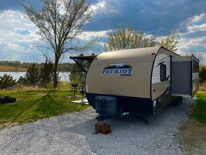 RV rental parked by a peaceful lakeside campsite, ready for your next nature and travel adventure.. Forest River Forrest River Cherokee Patriot Edition 26DBH 2015