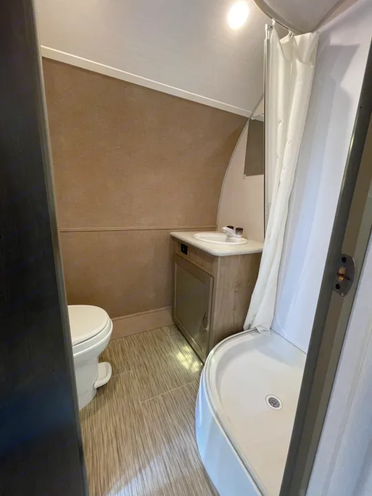 Clean RV rental bathroom featuring a toilet, sink vanity, and compact shower. Ideal for your next adventure!. Forest River R-Pod 2021