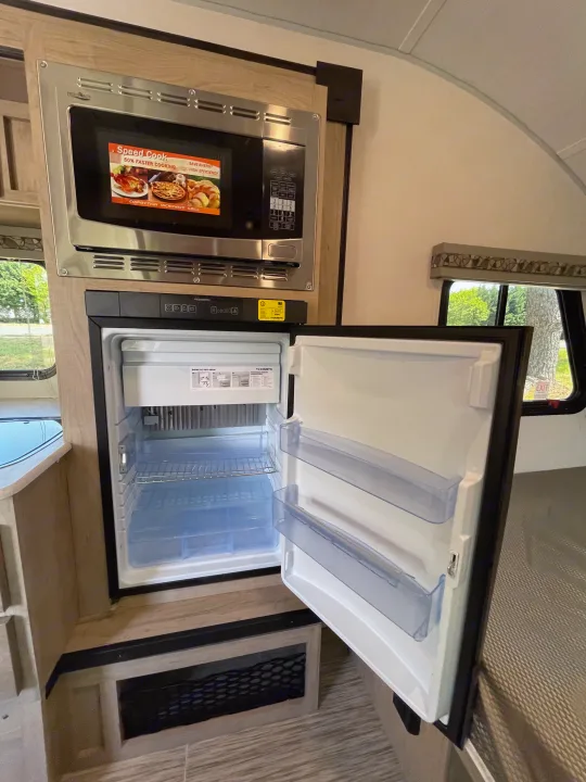 RV rental kitchen area featuring an open Dometic refrigerator and a "Speed Cook" microwave oven for easy meal prep.. Forest River R-Pod 2021