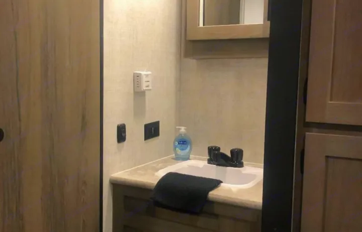 Inside this RV rental, find a tidy bathroom vanity with a sink, faucet, soap, towel, and essential wall-mounted controls.. Gulf Stream Ameri-Lite 2022