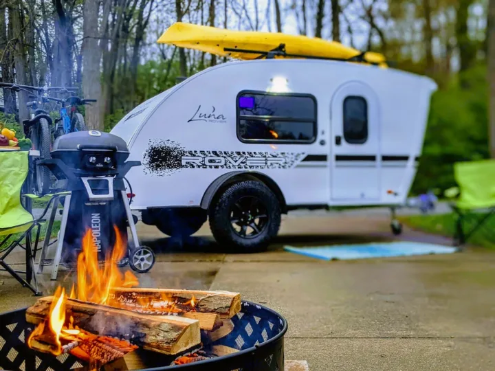 Cozy RV rental camp setup featuring a lively fire pit, Napoleon grill, bikes, and kayak on top for outdoor fun.. InTech RV InTech RV Trailer 2021