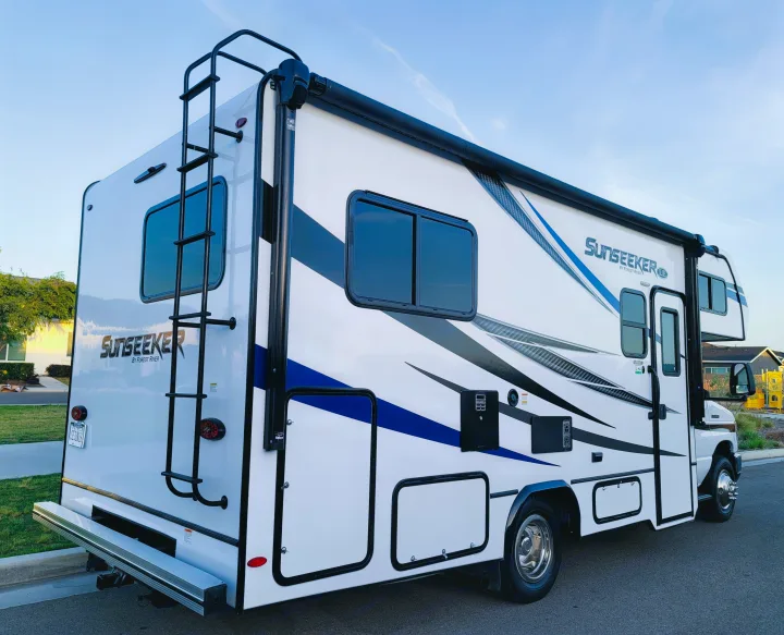 This spacious Sunseeker RV rental, featuring a white body with stylish blue/grey graphics and a rear ladder, is ready for your trip.. Forest River Sunseeker LE 2022