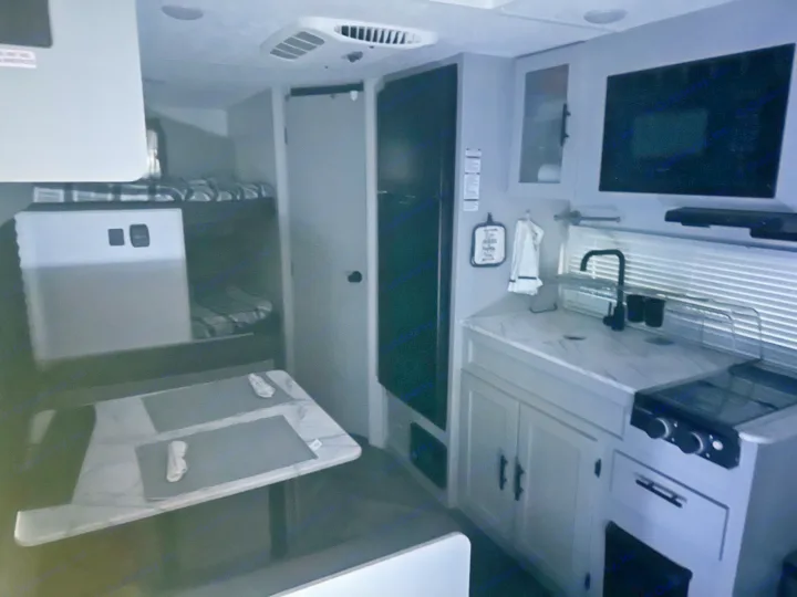 This rv rental interior features a compact kitchen, dining area, and bunk beds, optimizing space for travel.. Forest River Salem FSX PLATINUM 2021