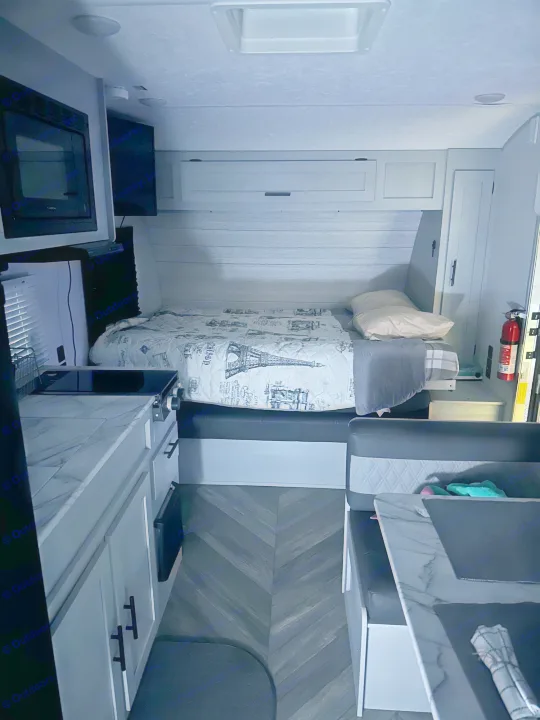 Modern RV rental interior with a cozy bed, compact kitchen, and dinette area. Perfect for your travels.. Forest River Salem FSX PLATINUM 2021