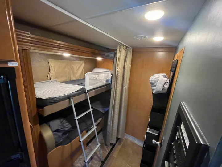 RV rental interior with cozy bunk beds, ladder, privacy curtain, and storage for a compact, comfortable stay.. Thor Chateau 2017